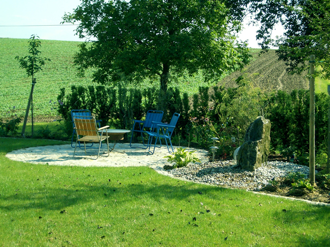 idyllische Sitzgelegenheit im schattigen Sommergarten, blaue rustikale Gartengarnitur