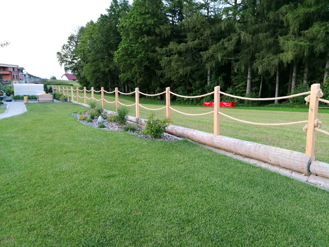 Zaun mit Holzpfeilern und gespannten Seilen als Abschluss des Gartens